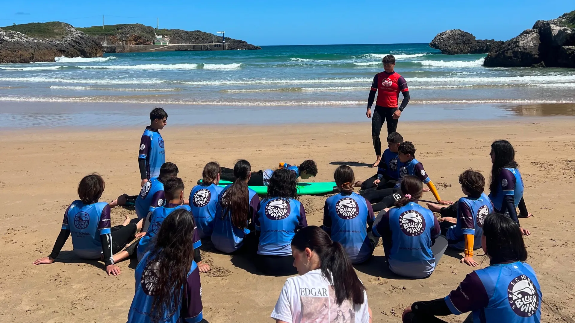 Viaje de fin de curso en Llanes para grupos escolares: clase de surf en la playa con monitores.
